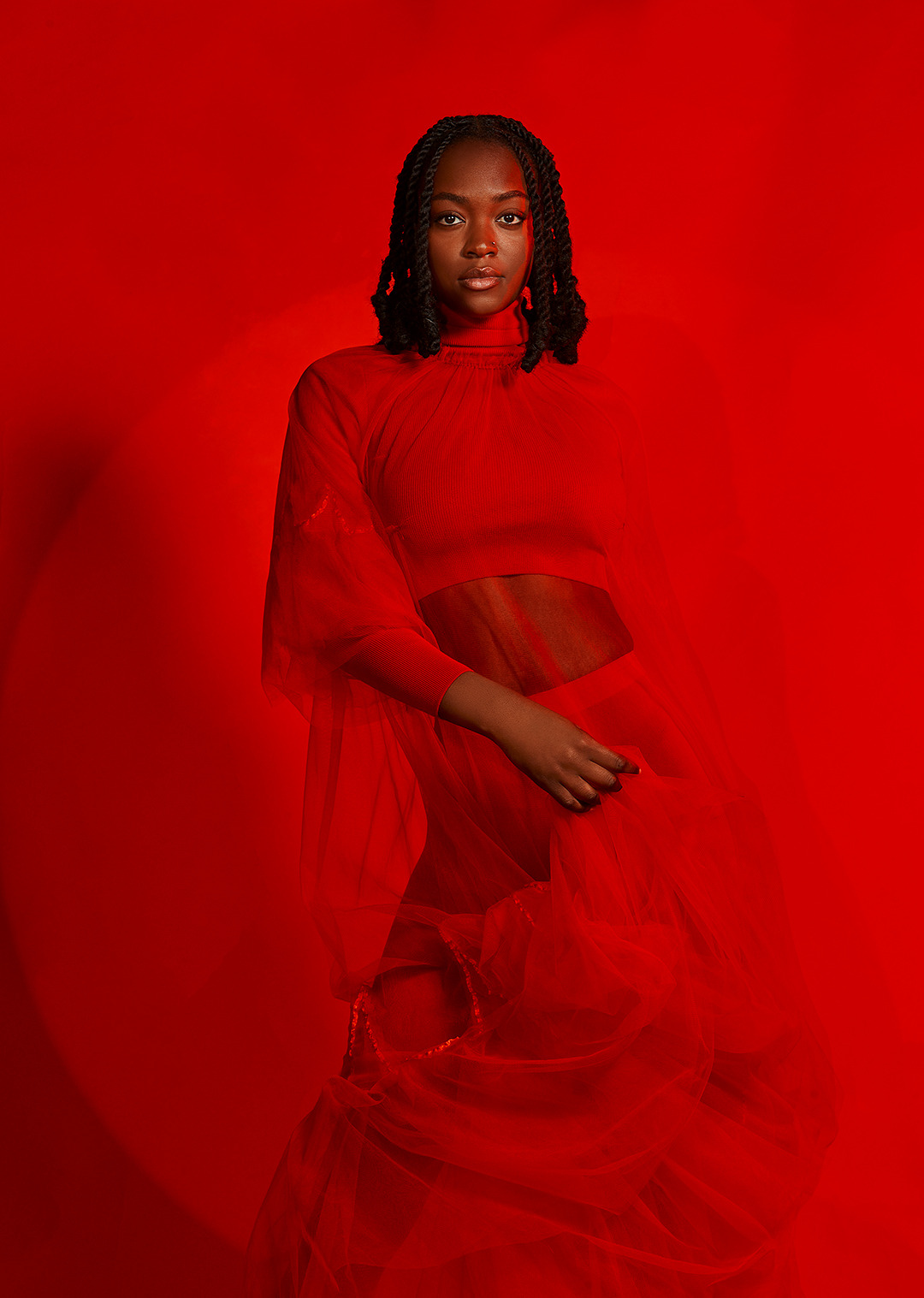 Fashion editorial of a model in flowing red tulle against a saturated red backdrop