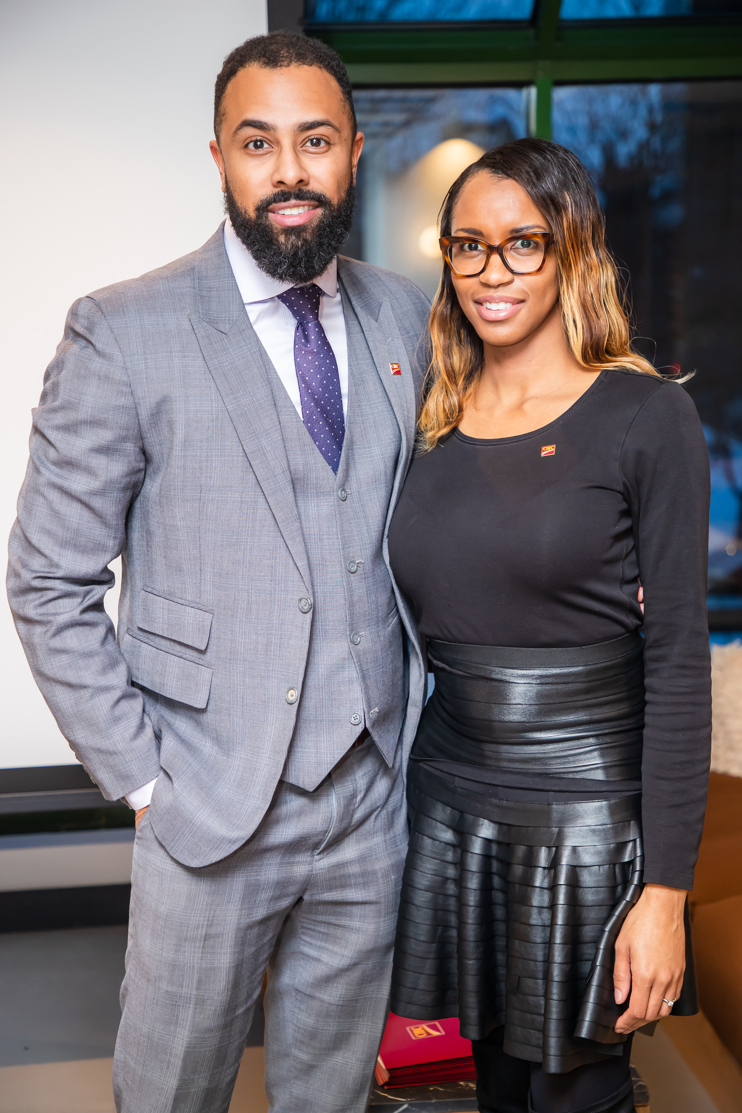Couple posing together at an event, he in a grey three-piece suit