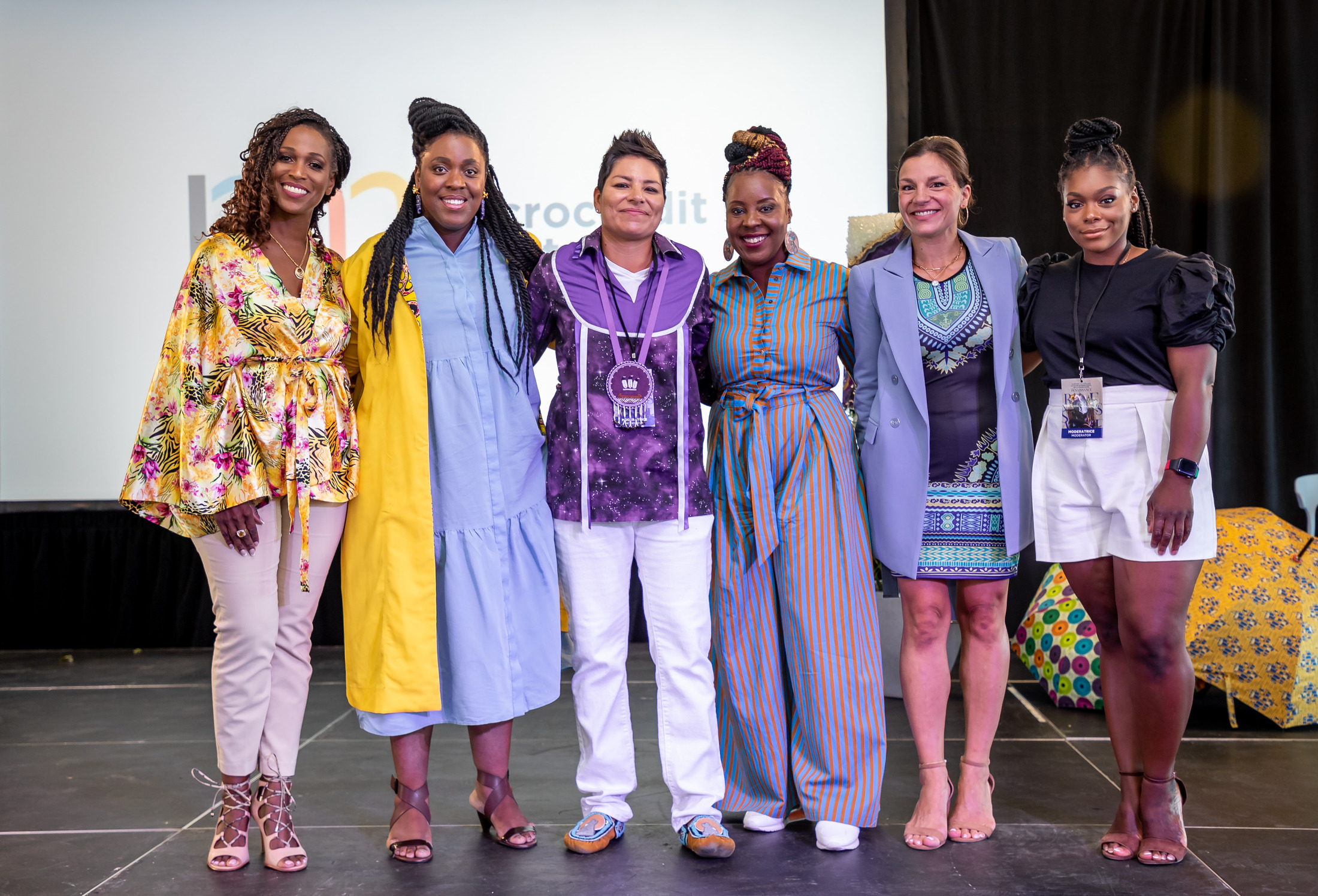 Group of women in colourful outfits posing on stage