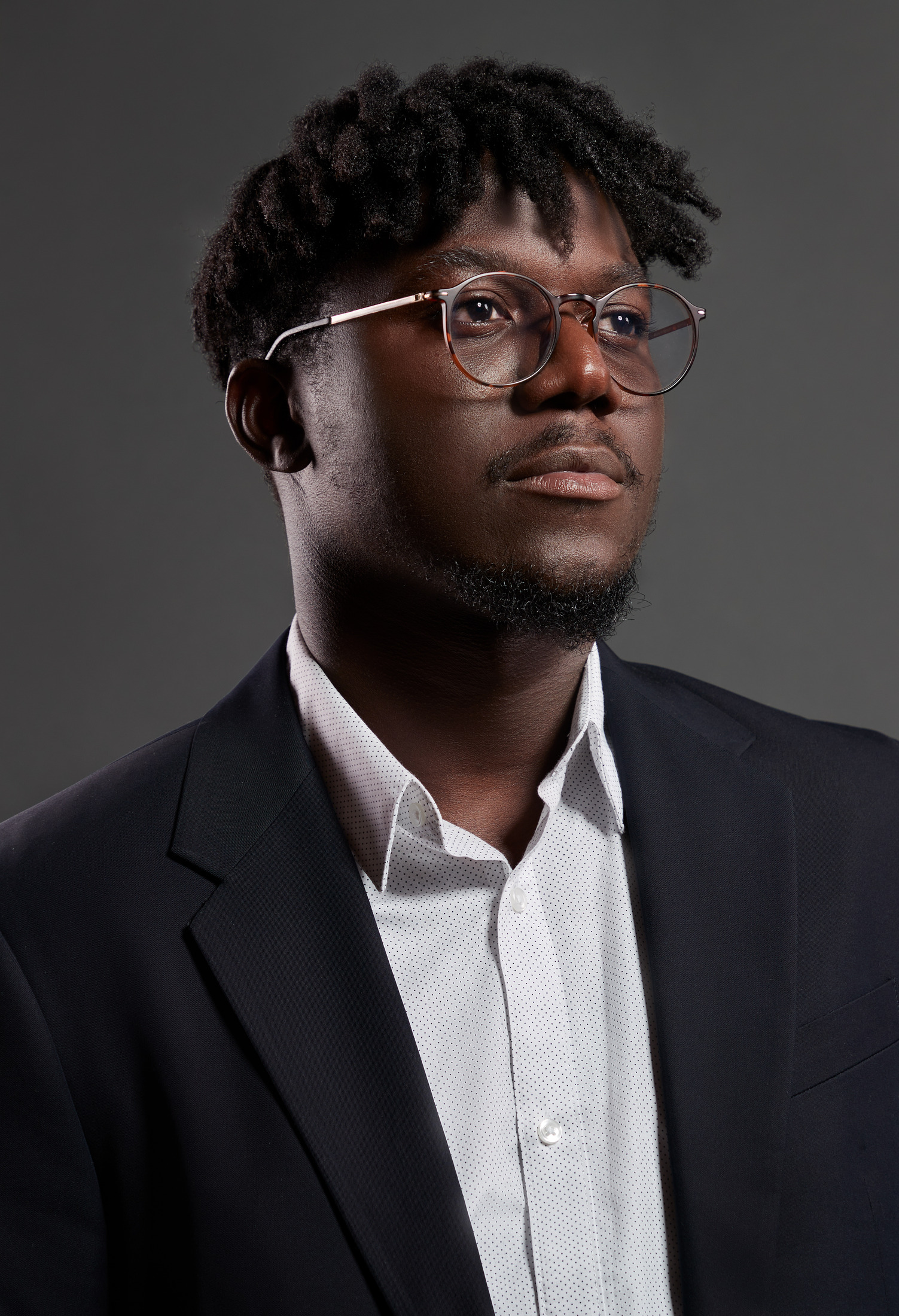 Close portrait of a man in a navy blazer and glasses, executive headshot