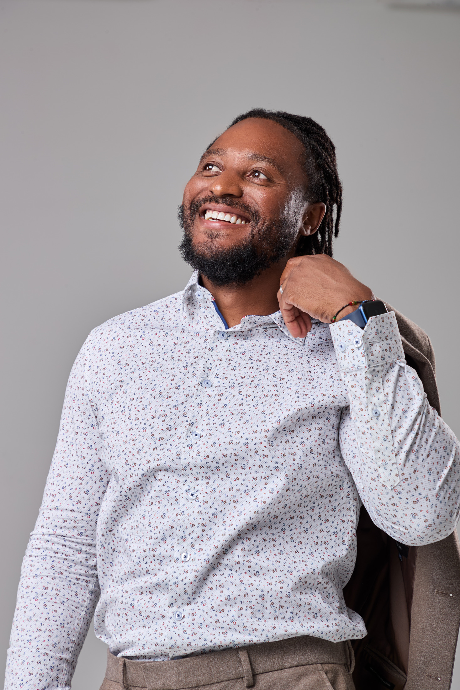 Man smiling and looking up with a jacket over his shoulder, studio portrait